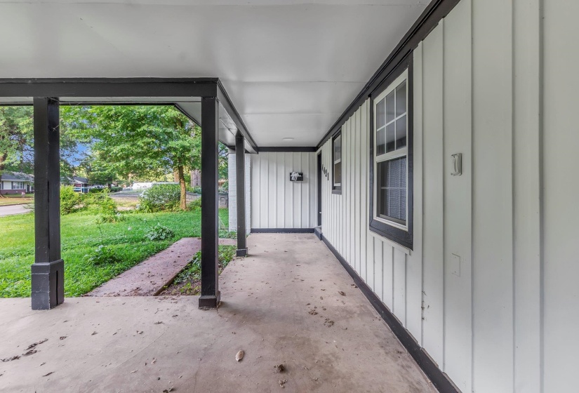Covered concrete porch with dark-painted support pillars and trim