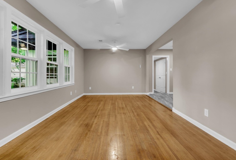 Expansive room featuring wood-finish flooring, neutral-toned walls, and multiple double-hung windows