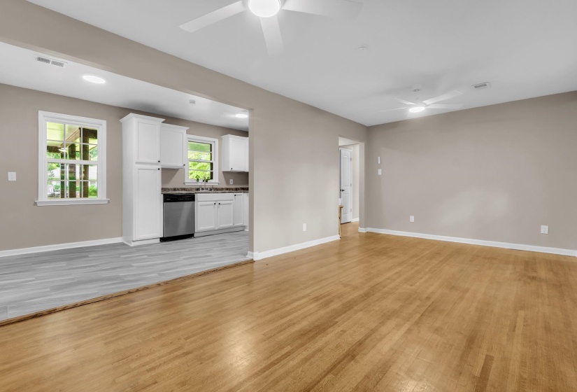 Expansive living area with wood-finish flooring, neutral wall paint, and a ceiling fan