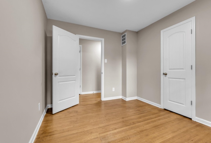 Hardwood flooring throughout, neutral wall paint, white trim, and white paneled doors
