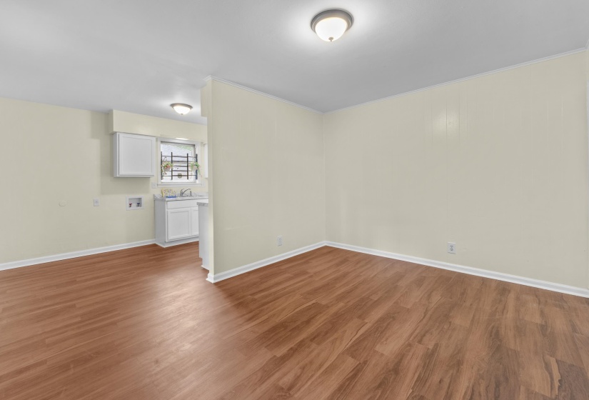 Spacious interior room featuring wood-finish flooring, light-toned walls, white baseboards, and a semi-flush mount ceiling light