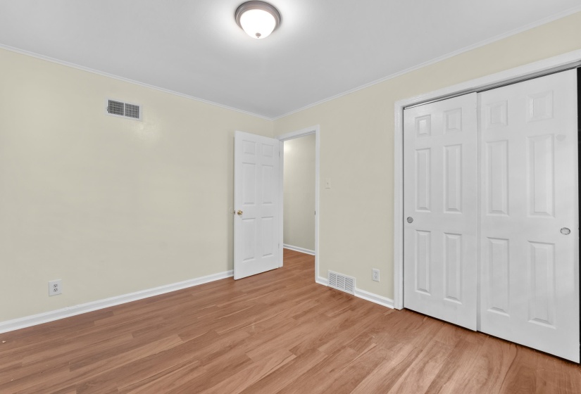 Bedroom featuring wood-finish flooring, light-toned walls, and white trim