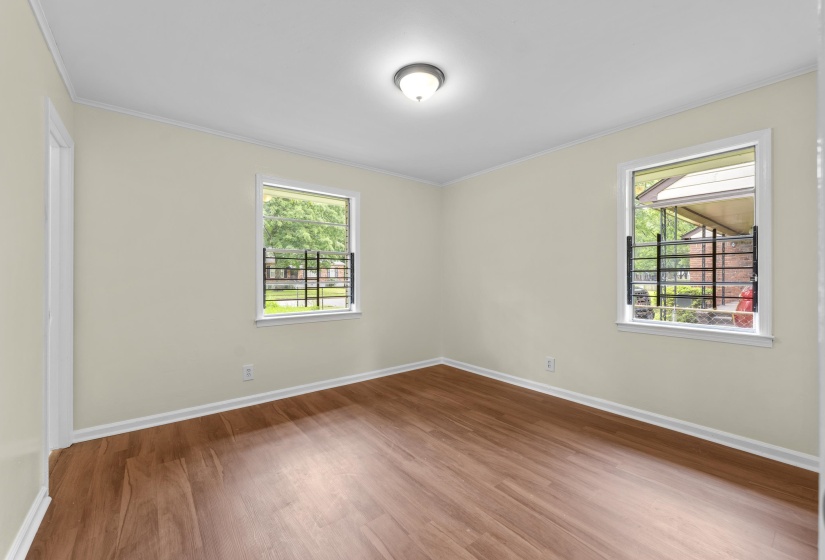 Bright room featuring two windows, wood-finish flooring, and white trim