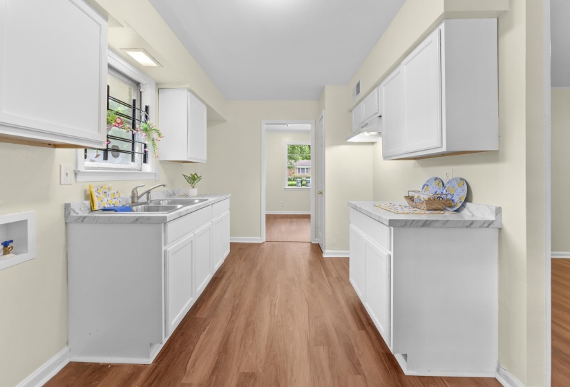 Kitchen featuring white cabinetry, wood-finish flooring, a double basin sink, and laminate countertops