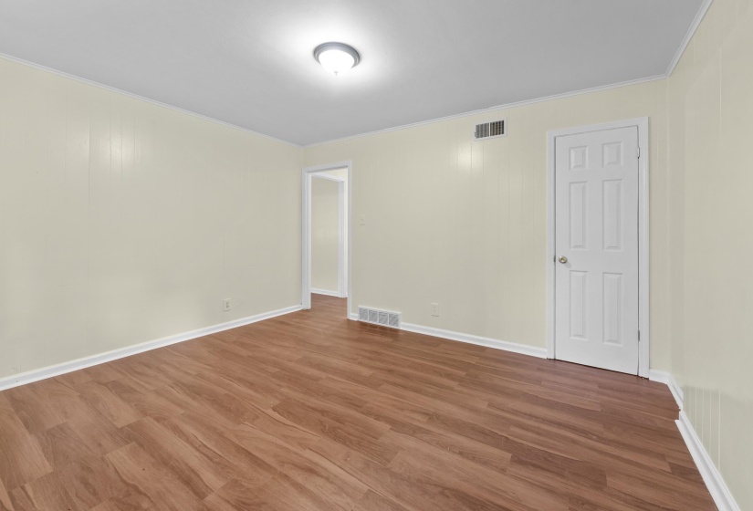 Spacious room featuring wood-finish flooring, light-toned walls with vertical paneling, and white trim