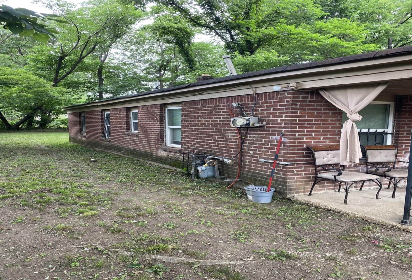 Brick exterior featuring multiple windows and a covered patio area