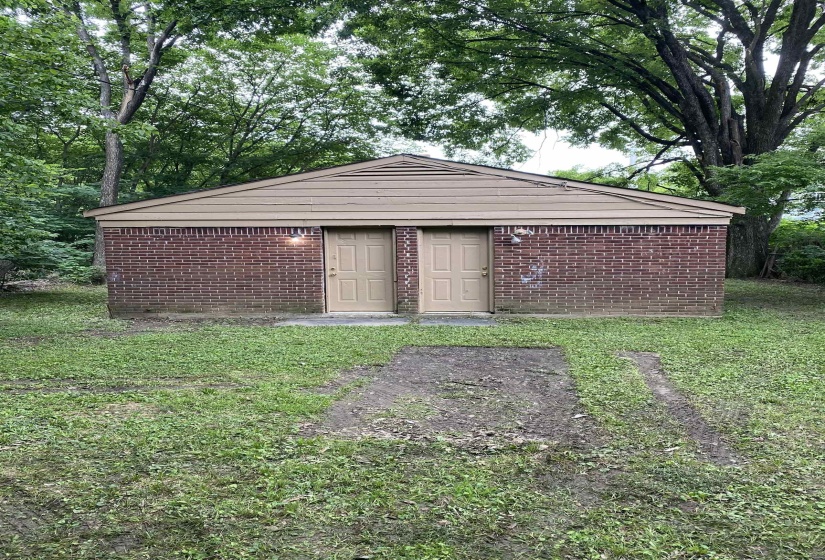 Brick structure with two entry doors, light-toned wood paneling, and a pitched roof