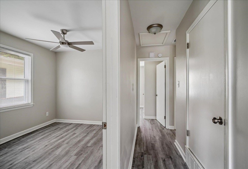 Interior room featuring wood-finish flooring, a ceiling fan, and a window with blinds
