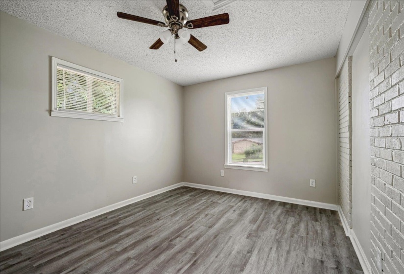 Interior room featuring wood-finish flooring, two windows, and a ceiling fan with light fixture