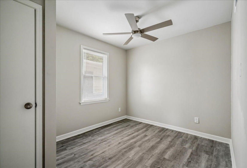 Room featuring wood-finish flooring, a contemporary ceiling fan with integrated lighting, and a window with blinds