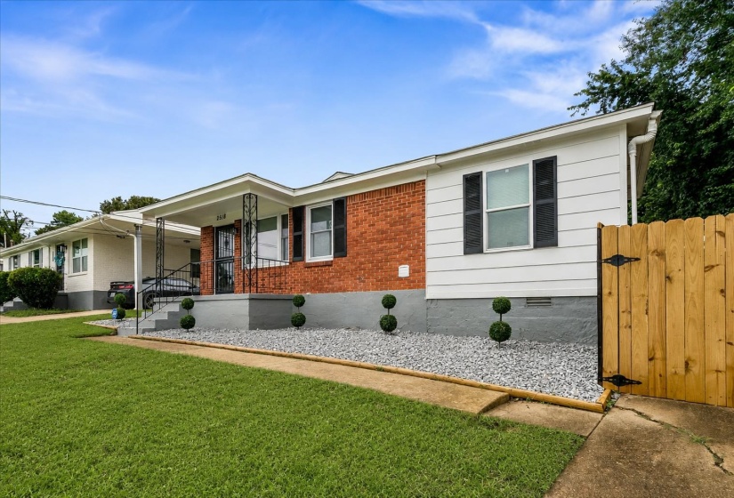 Brick and white siding exterior with a covered front porch featuring wrought iron columns