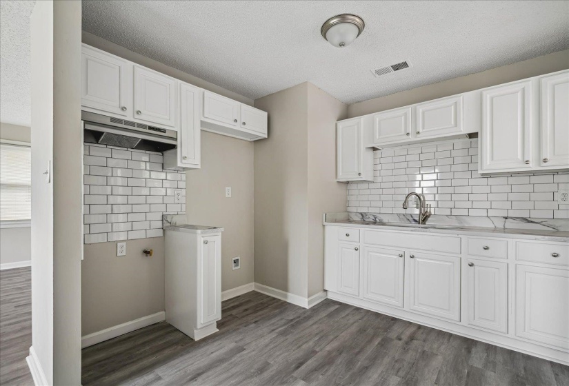 Kitchen featuring white shaker-style cabinetry, a subway tile backsplash, and a sink with a gooseneck faucet