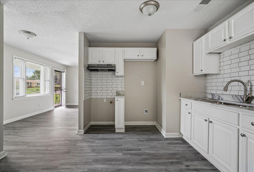 Kitchen featuring white cabinetry, subway tile backsplash, and wood-finish flooring