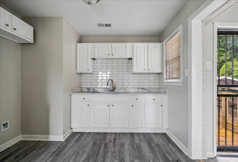 Kitchenette featuring white cabinetry, subway tile backsplash, and light-toned countertops