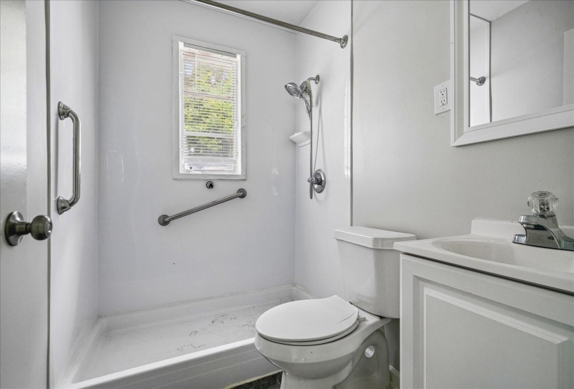 Bathroom featuring a white shower with an integrated window, a white toilet, and a vanity with an integrated sink