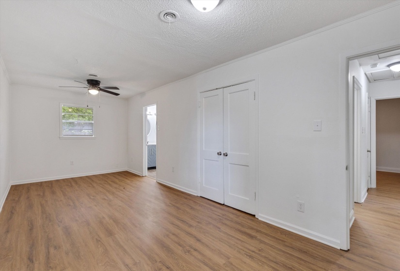 Spacious room with wood-finish flooring, white walls, and a ceiling fan