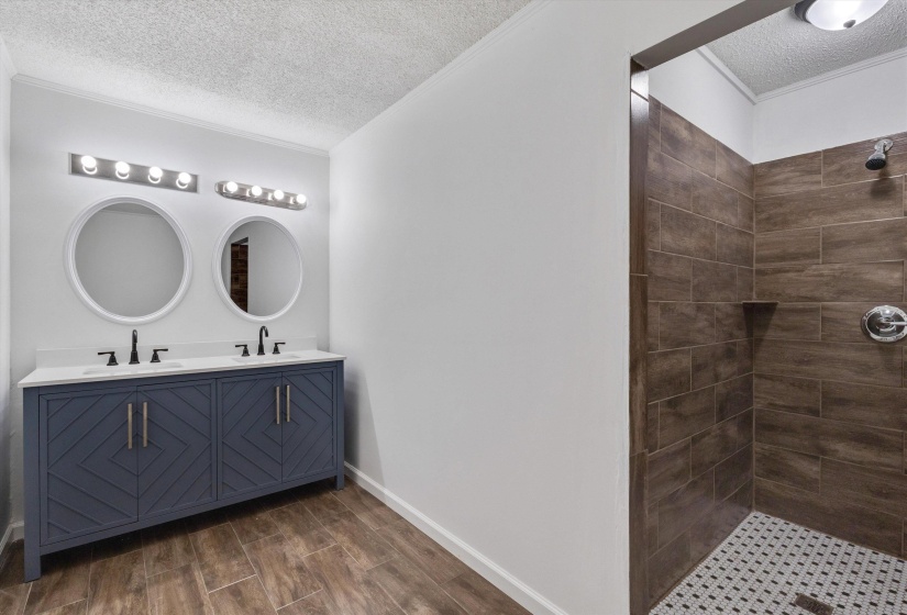 Bathroom featuring a dual vanity with a blue cabinet and white countertop, twin round mirrors, and wood-finish flooring
