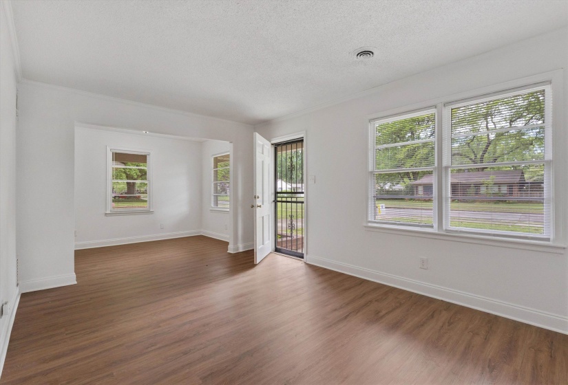 Open-concept room featuring wood-finish flooring, white baseboards, and multiple windows with horizontal blinds