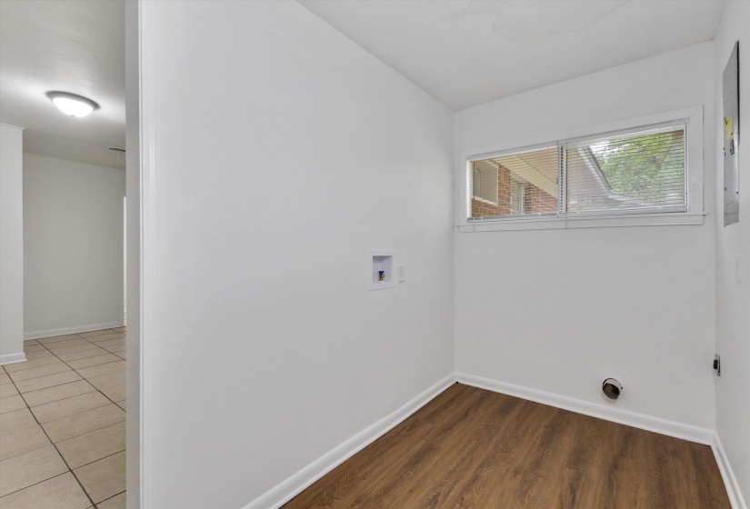 Utility room featuring wood-finish flooring, white walls, and a multi-pane window