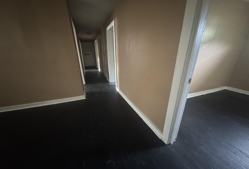 Interior hallway featuring dark-finish flooring, light-toned walls, and white trim