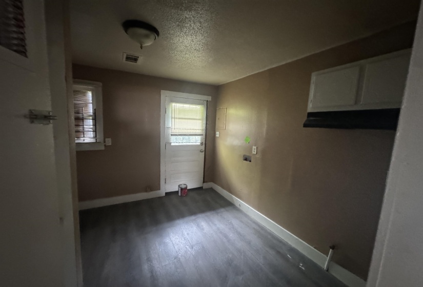 Room featuring wood-finish flooring, a ceiling-mounted light fixture, and a window with blinds