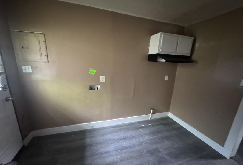 Utility area featuring wood-finish flooring, a wall-mounted cabinet, and dedicated appliance hookups