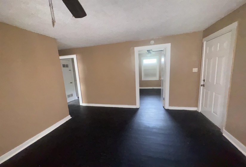 Interior space featuring dark wood-finish flooring, light tan walls, and white trim