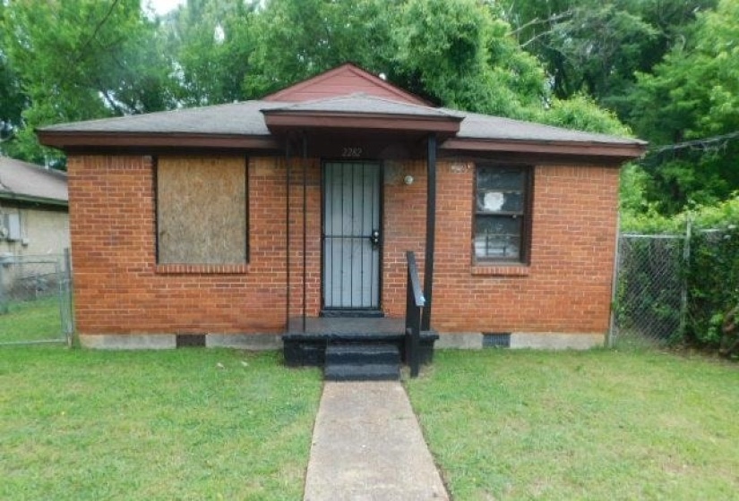 Brick exterior with a covered entry, concrete steps, and a wrought iron security door