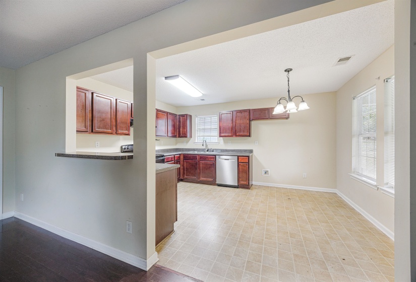 Kitchen with dark brown cabinets, decorative light fixtures, a chandelier, dark countertops, and dishwasher