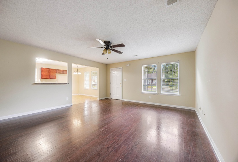 Unfurnished room featuring dark wood-style flooring, a textured ceiling, ceiling fan, and a chandelier
