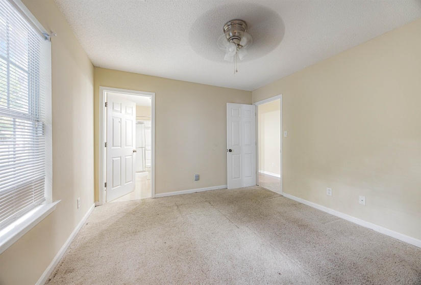 Unfurnished bedroom with carpet floors, a textured ceiling, a ceiling fan, and ensuite bath