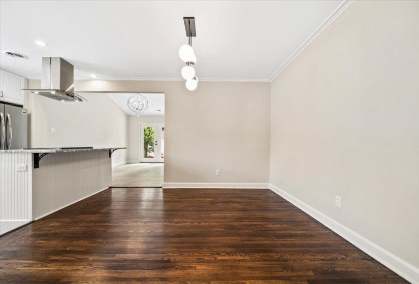 Dining area featuring dark wood-finish flooring, light neutral wall paint, and white crown molding