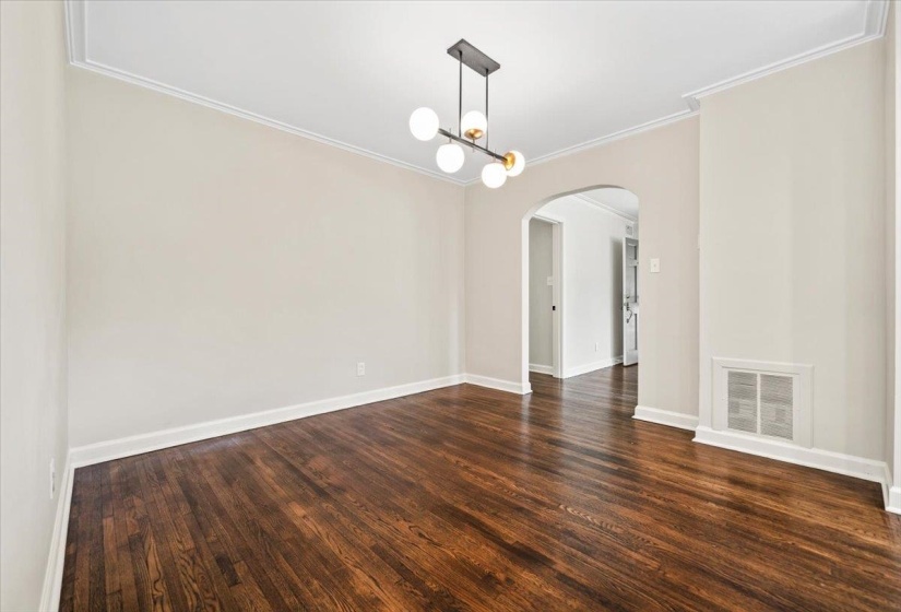 Spacious room featuring dark wood-finish flooring, light neutral-toned walls, and a modern ceiling light fixture