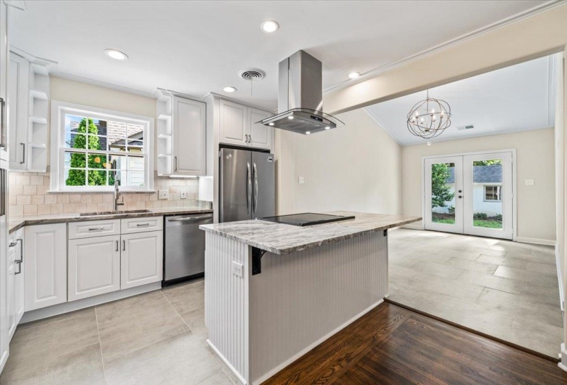 Modern kitchen featuring white shaker cabinetry, stainless steel appliances, a center island with cooktop, recessed lighting, and tile flooring