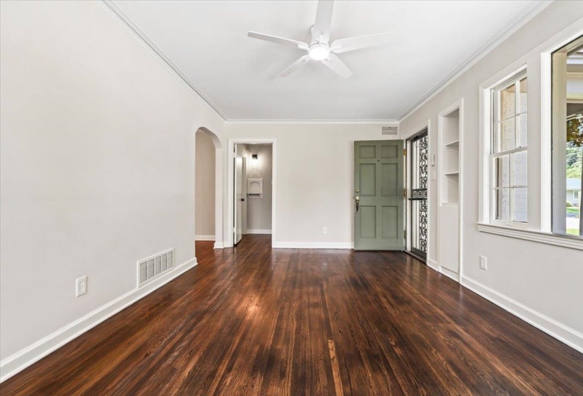 Spacious interior with dark wood-finish flooring, white walls, and white ceiling fan