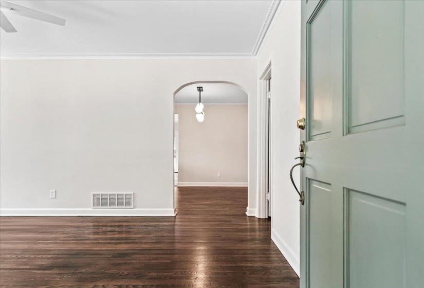 Entryway with a light blue paneled door, brass hardware, and dark wood-finish flooring