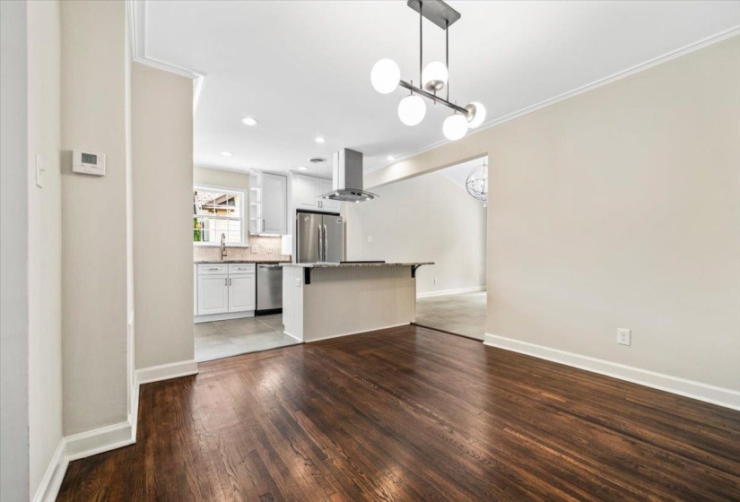 Expansive wood-finish flooring extends throughout, complemented by a contemporary chandelier