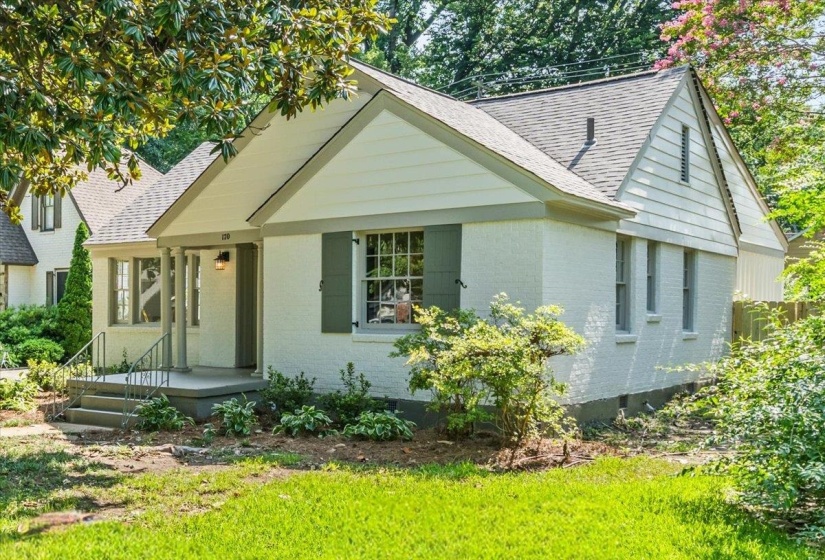 White brick exterior with a gray-shingled roof and dark gray shutters