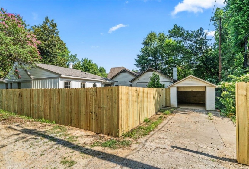 Newly installed privacy fencing enclosing a concrete driveway and detached garage