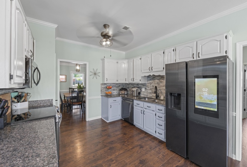 Kitchen featuring wood-finish flooring, light cabinetry with dark hardware, stone countertops, and a tile backsplash