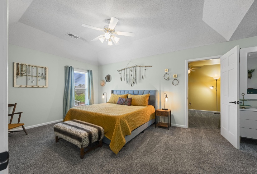 Carpeted bedroom featuring a tray ceiling with a ceiling fan