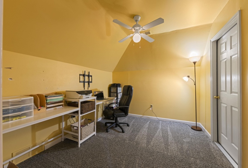 Attic room featuring a sloped ceiling, gray carpet, and a ceiling fan with integrated lighting