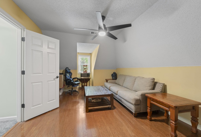 Hardwood-finish flooring, a modern ceiling fan, and a paneled white door