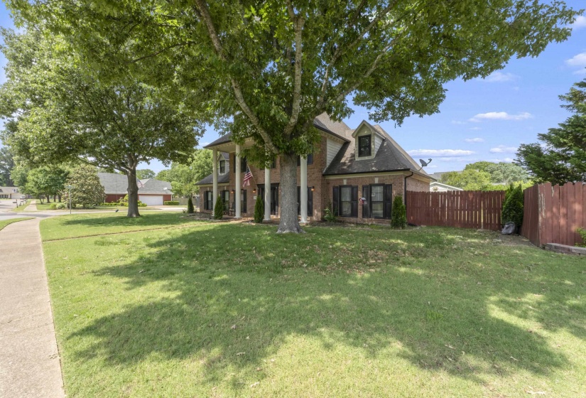 Traditional brick residence featuring a portico entry supported by columns, dark shutters, and a dormer window