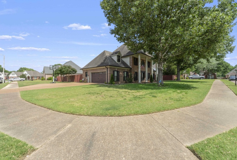 Two-story brick residence featuring a columned front porch, a multi-pane front door, and an attached two-car garage