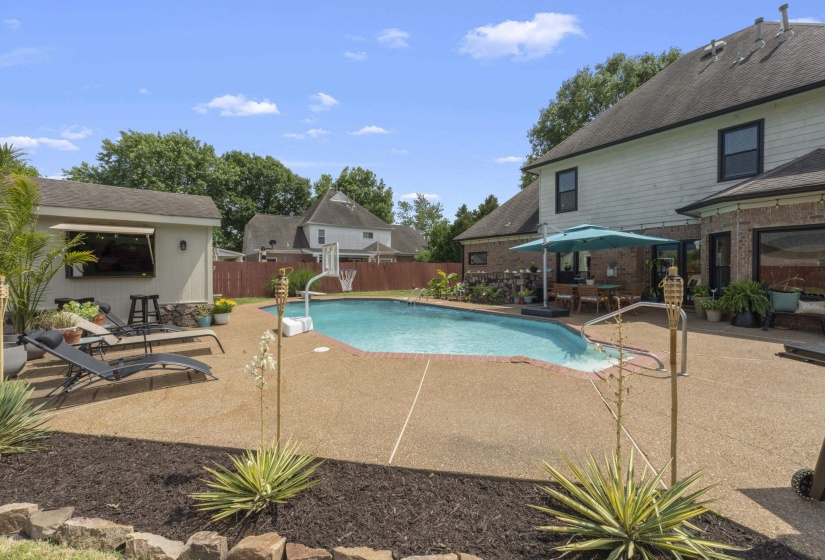 Backyard oasis featuring an in-ground swimming pool with an exposed aggregate concrete deck
