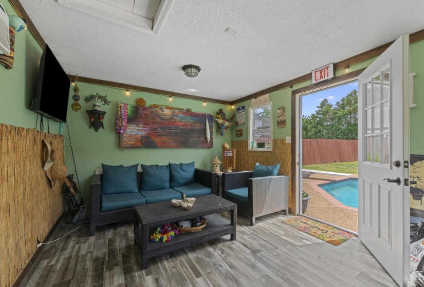 Indoor-outdoor living space featuring wood-finish flooring, a white paneled door with glass inserts, and direct access to a backyard with a swimming pool