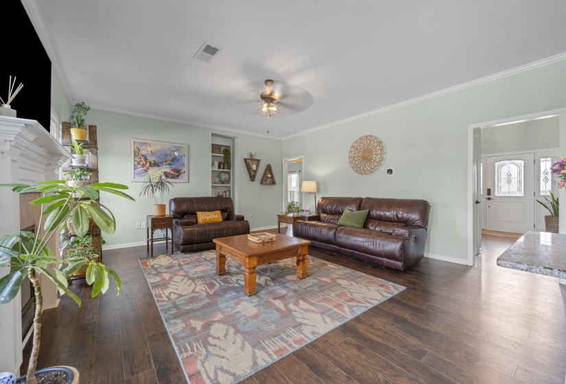 Spacious living area featuring wood-finish flooring, light-toned walls, and crown molding