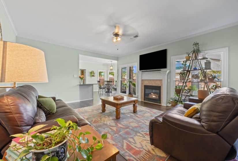 Living room featuring a fireplace with a stone surround and a white mantle, wood-finish flooring, and white trim