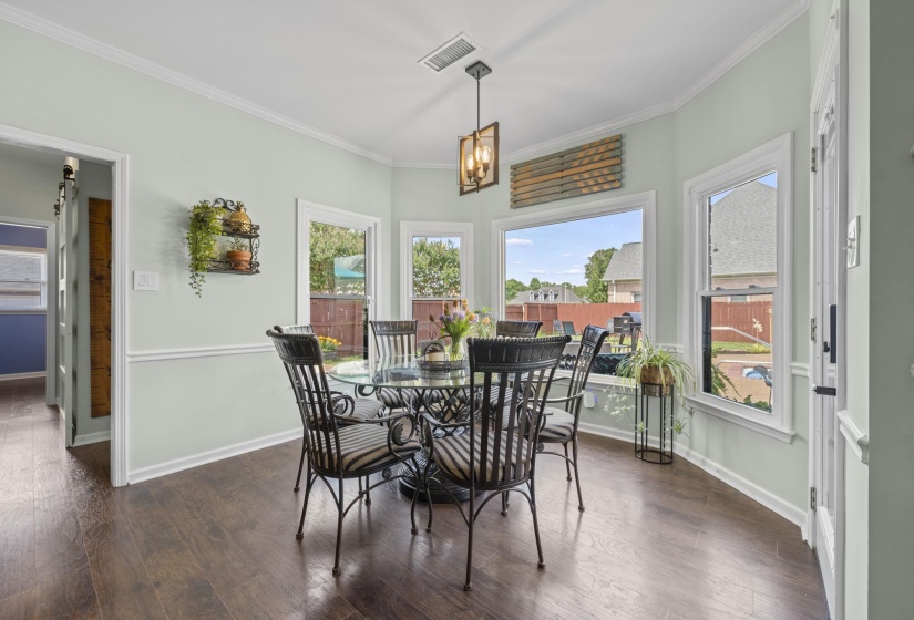 Dining area featuring dark wood-finish flooring, light-toned walls with chair rail molding, and a bay window configuration